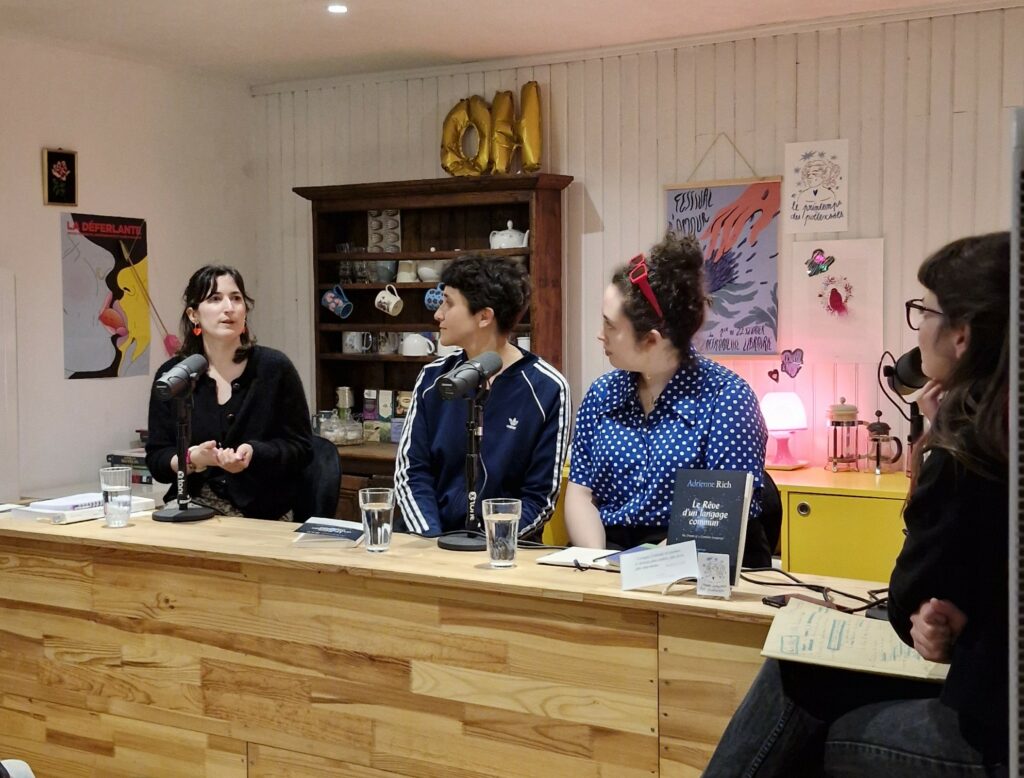 quatre personnes sont assises à un comptoir avec des micros devant elles. elles regardent toutes la personne la plus à gauche qui est en train de parler